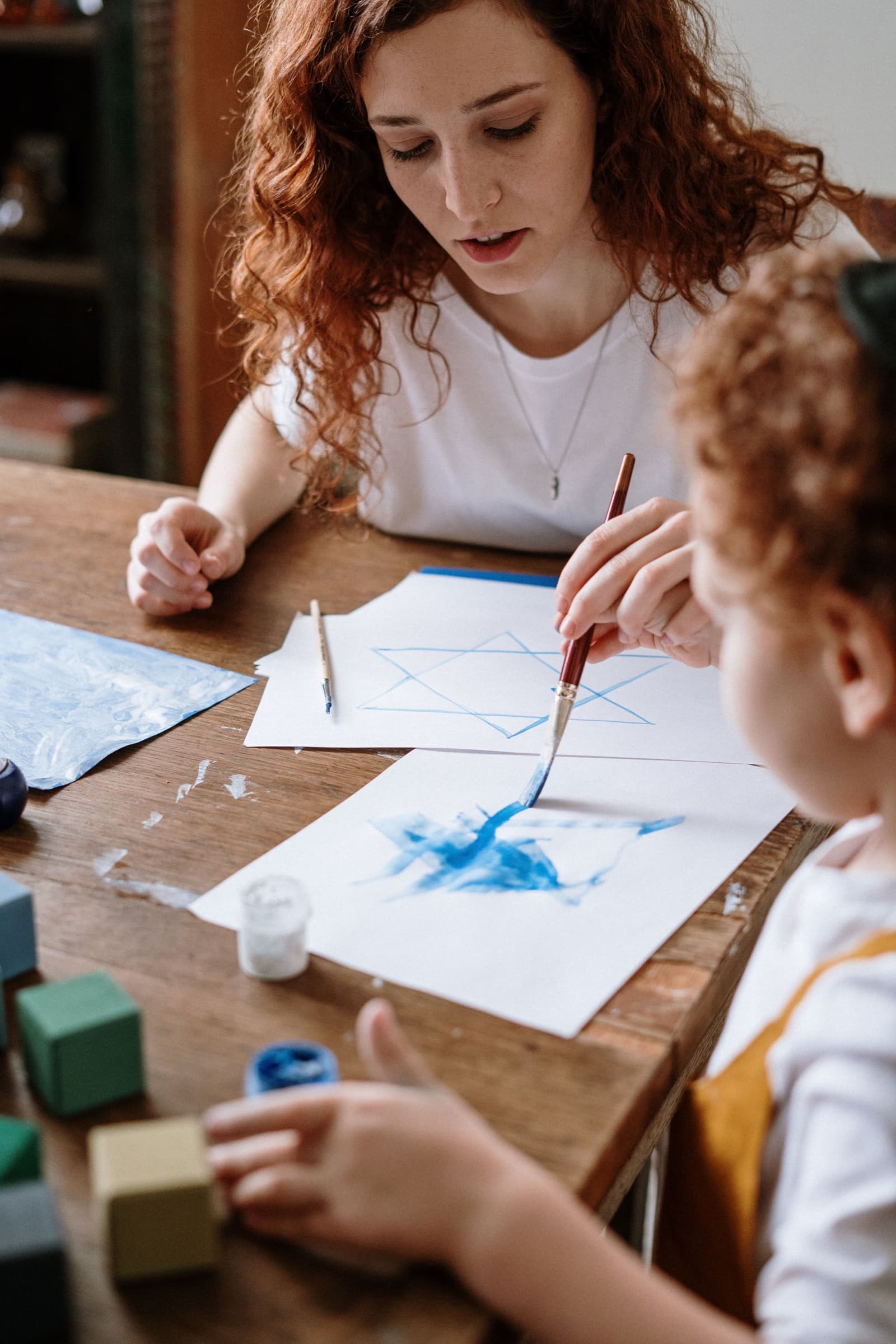 A caregiver and young child painting together at home