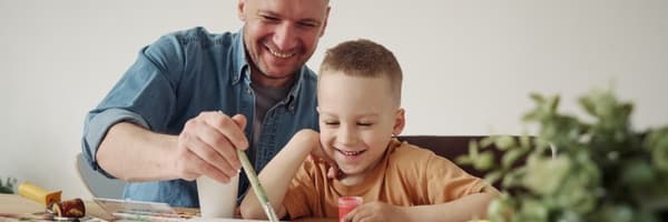 A parent and child painting together at home